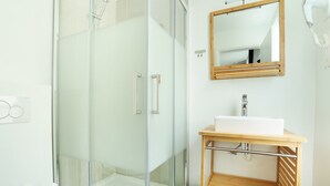 A modern bathroom with a glass-enclosed shower, a wooden vanity with a sink, and a mirror above the vanity. - Meslay 8 - Studio Apartment, Sleeps 2 (Paris)
