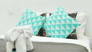 A neatly made bed with a grey and white striped bedspread, two teal and white patterned pillows, and a white towel on the bed. - Meslay 9 - One Bedroom Apartment, Sleeps 4 (Paris)