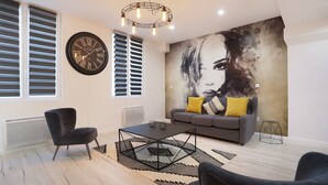 Una sala de estar moderna con un cuadro abstracto grande, un reloj de pared redondo y una lámpara de araña contemporánea.