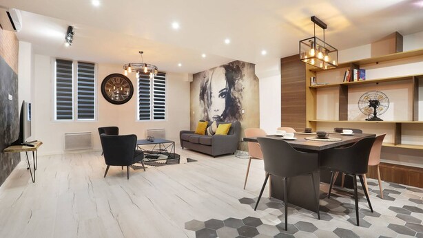 Una sala de estar moderna con comedor, un cuadro abstracto grande y una estantería.