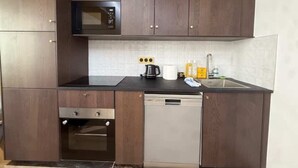 A kitchen with dark wooden cabinets, a microwave, an oven, a dishwasher, and a sink with a faucet. - St Denis 2 - One Bedroom Apartment, Sleeps 6 (Paris)