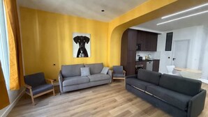 A living room with a sofa, chairs, and a painting on the wall. - St Denis 2 - One Bedroom Apartment, Sleeps 6 (Paris)