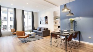 Un salon moderne avec un canapé, une table à manger, des chaises et une grande fenêtre.
