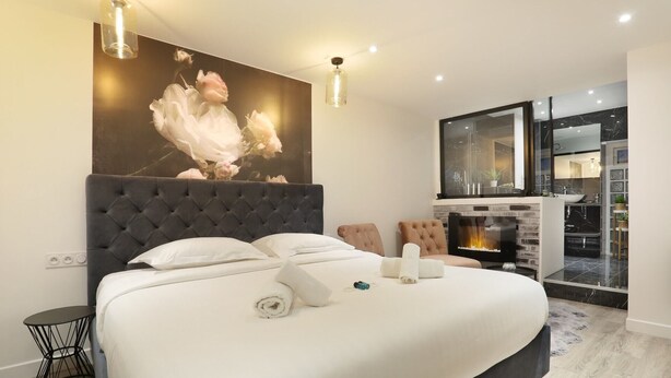 A bedroom with a large bed, a fireplace, and a view of the kitchen. - St Honore - Two Bedroom Apartment, Sleeps 6 (Paris)