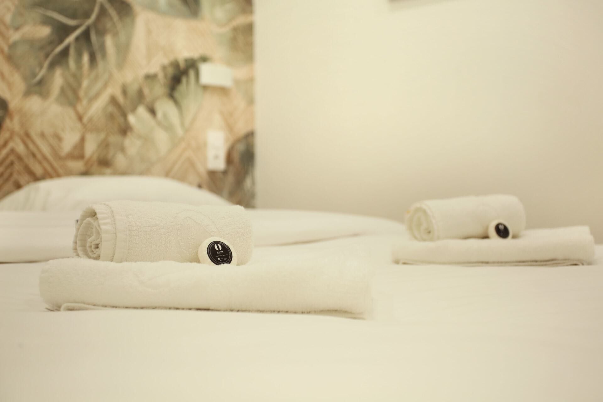 Neatly folded white towels with black buttons on a bed.