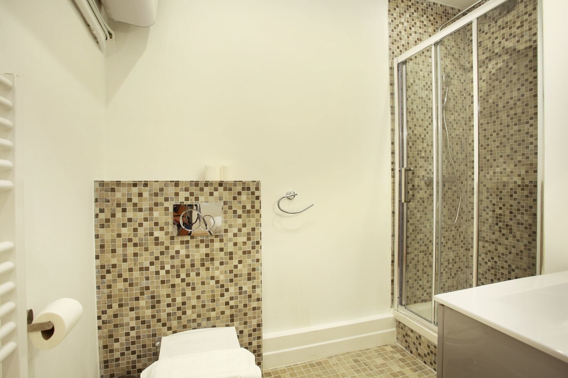 Un baño con inodoro, ducha con puerta de vidrio y lavamanos.