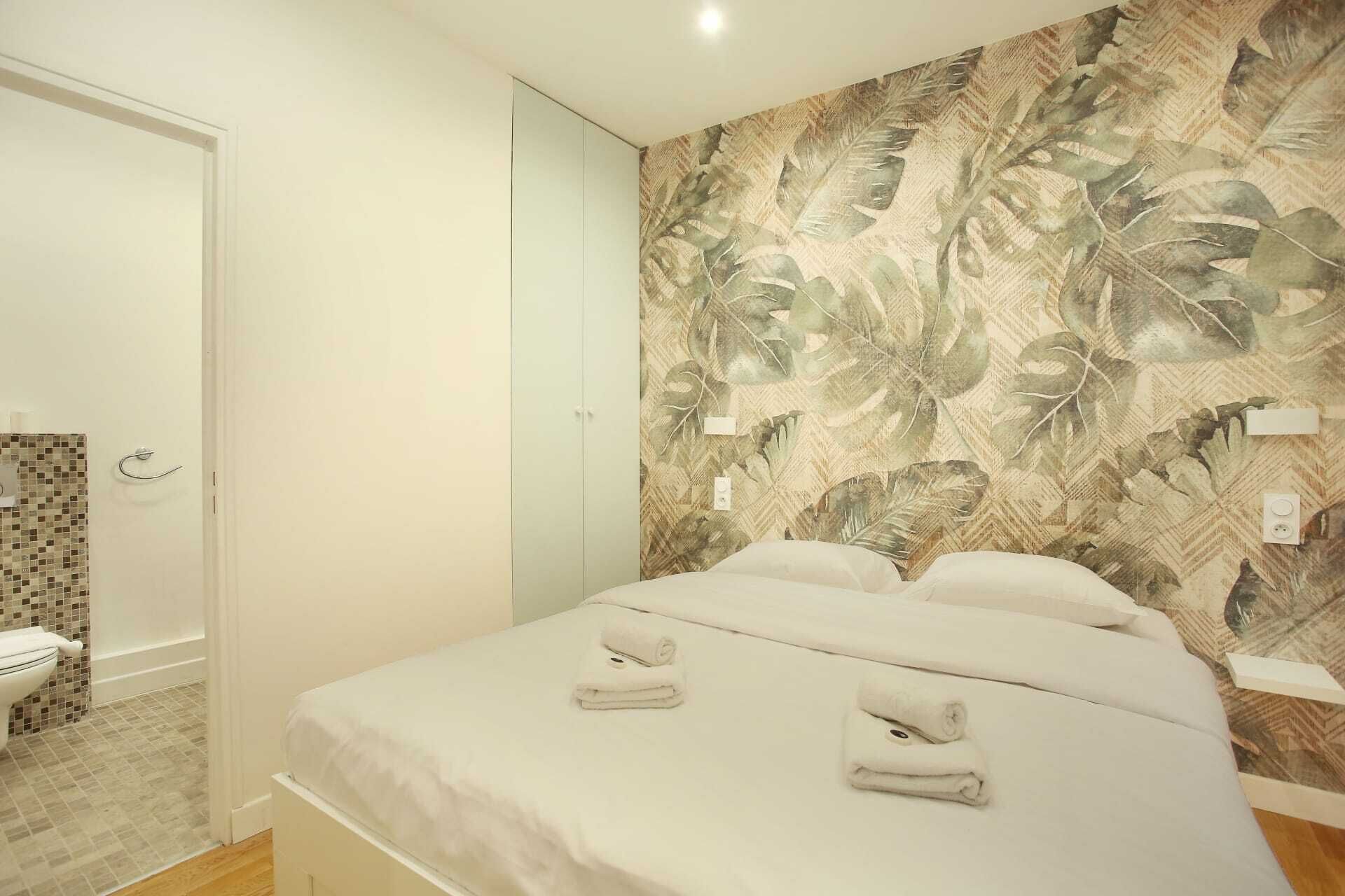 Une chambre avec un lit, deux serviettes, une douche et des toilettes.