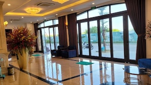 A spacious lobby with a marble floor, large windows, and a chandelier. - ViNH KHANG HA LONG HOTEL (Bai Chay)