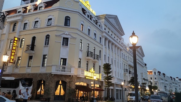 A historic hotel with classical architecture, a prominent entrance, and a well-lit street corner. - ViNH KHANG HA LONG HOTEL (Bai Chay)