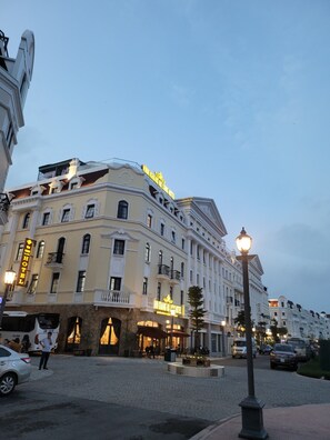 Un hôtel historique à l’architecture classique, doté d’une entrée imposante et situé à un carrefour bien éclairé.