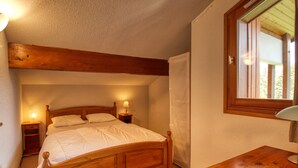 Un dormitorio con una cama de madera, lámparas de noche, una mesita de noche de madera y una ventana.