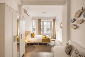 Una habitación de hotel con cama, sofá, escritorio y armario.
