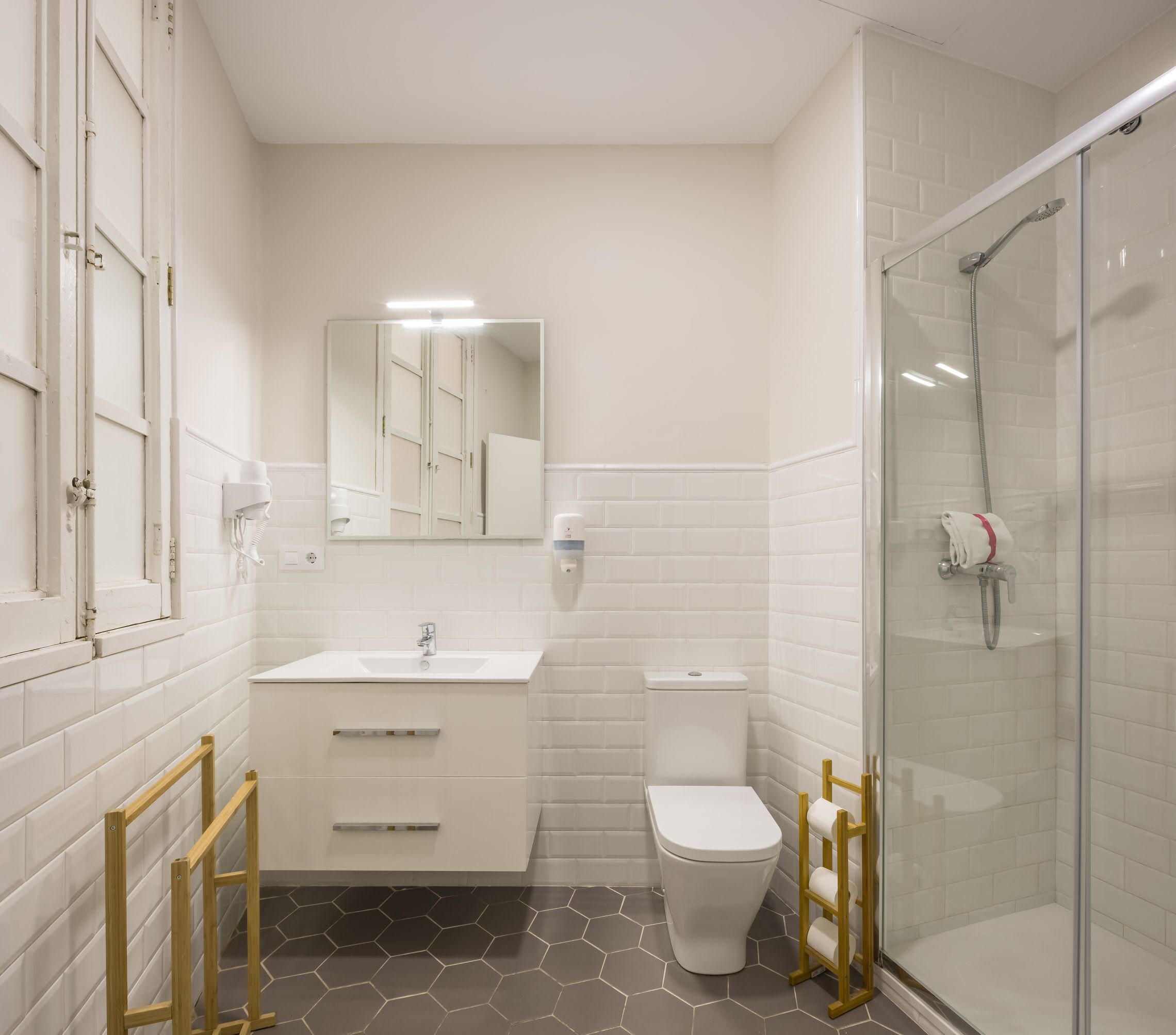 A modern bathroom with a white vanity, a toilet, a shower area, and a mirror.