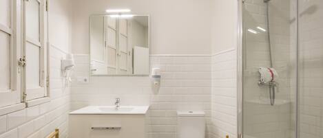 A modern bathroom with a white vanity, a toilet, a shower area, and a mirror.