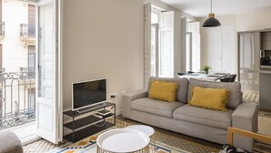 A modern living room with a sofa, TV, and pendant lights. - Macflats Ayuntamiento (Valencia)