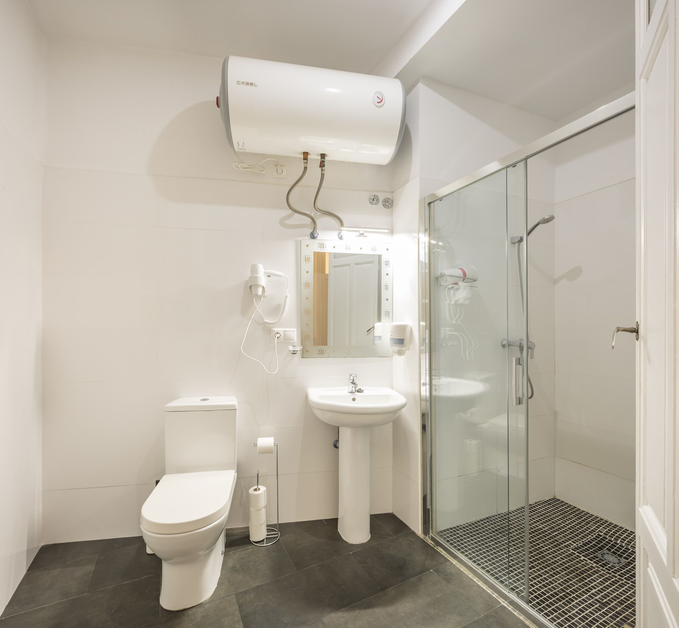 A bathroom with a toilet, sink, and glass shower enclosure.