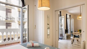 A hotel room with two beds, a balcony, a dining area, and a view of the city. - Macflats Ayuntamiento (Valencia)