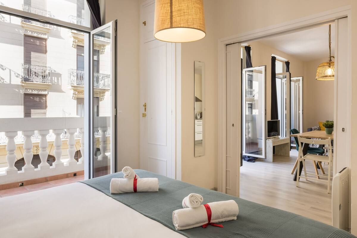 Hotellihuone, jossa on kaksi sänkyä, parveke, ruokailutila ja näkymä kaupunkiin.