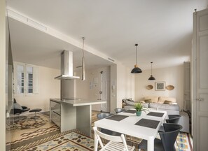 A modern kitchen with a white countertop, stainless steel range hood, and pendant lights. - Macflats Ayuntamiento (Valencia)