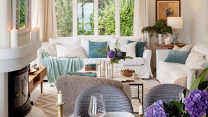 Un salon chaleureux avec une cheminée, un ensemble de canapés et un coin repas agrémenté de bougies et de fleurs.