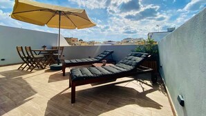 A rooftop terrace with a table and chairs, two sun loungers, and a large umbrella. - 248 Boutique Studios (Sliema)