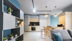 A modern kitchen with built-in appliances, a dining area with a wooden table and chairs, and a living area with a sofa and cushions. - 248 Boutique Studios (Sliema)