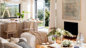A modern living room with a sofa, dining table, and a TV. - Wishome—A special villa to extend your summer at Oyambre Beach, Comillas (San Vicente de la Barquera)