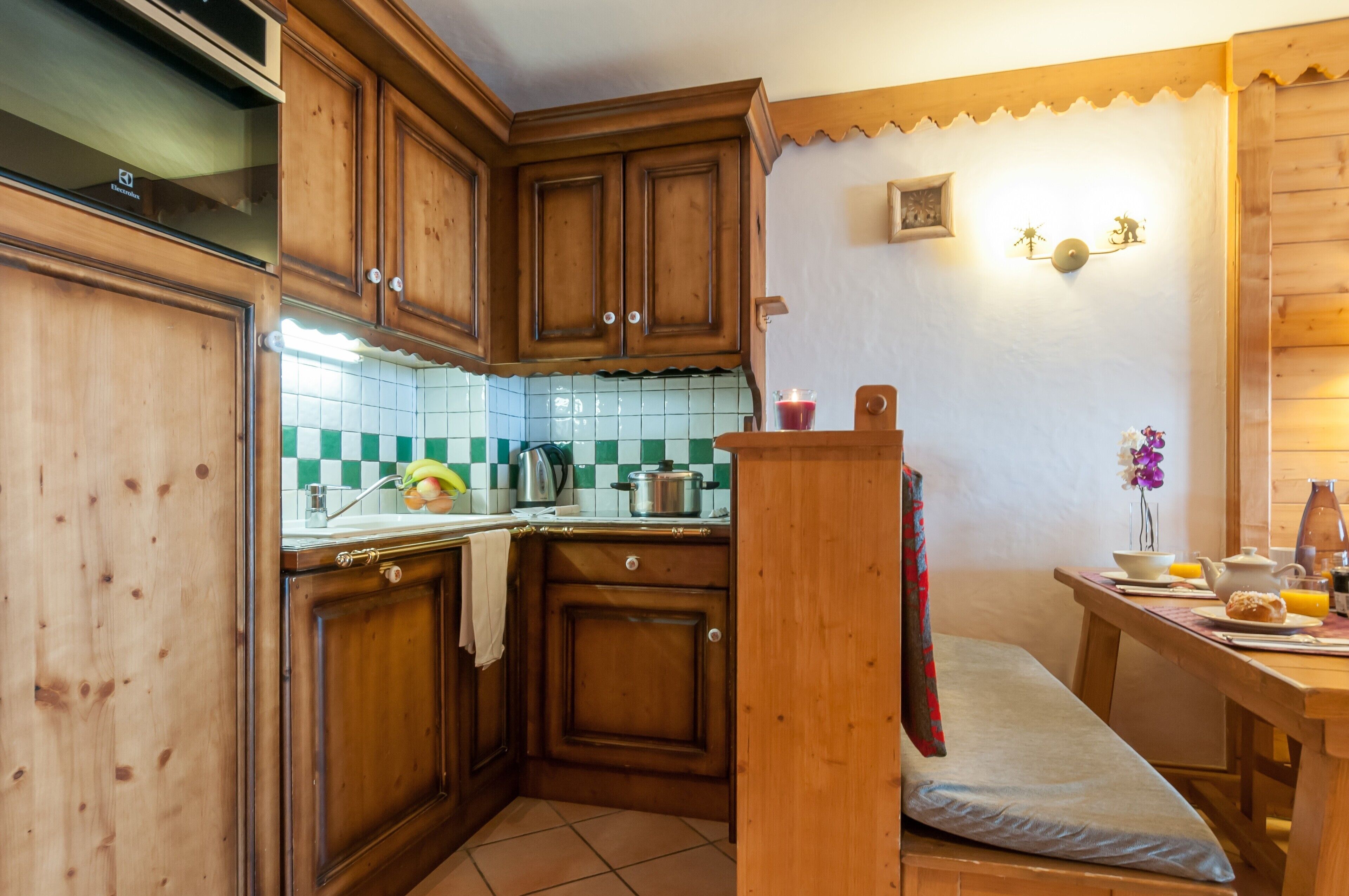 Una cocina con armarios de madera, salpicadero de azulejos y una mesa de desayuno con un florero.
