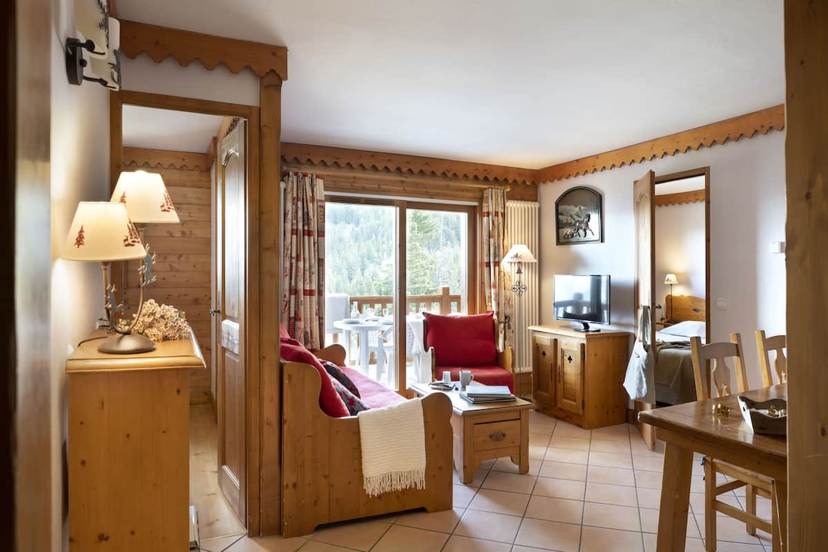 A cozy wooden interior with a sofa, dining table, and a TV.
