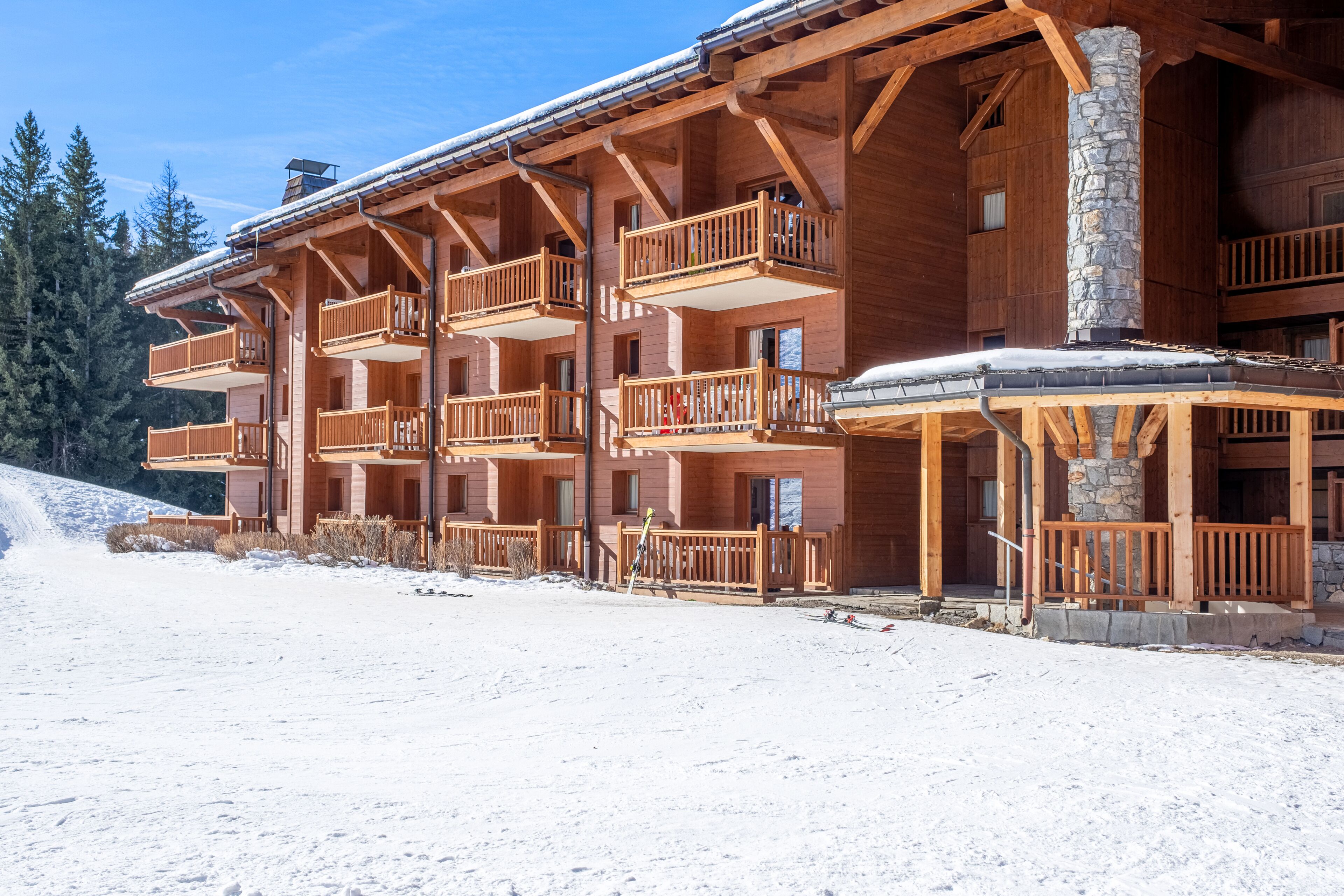 A multi-story wooden lodge with balconies and a stone chimney.