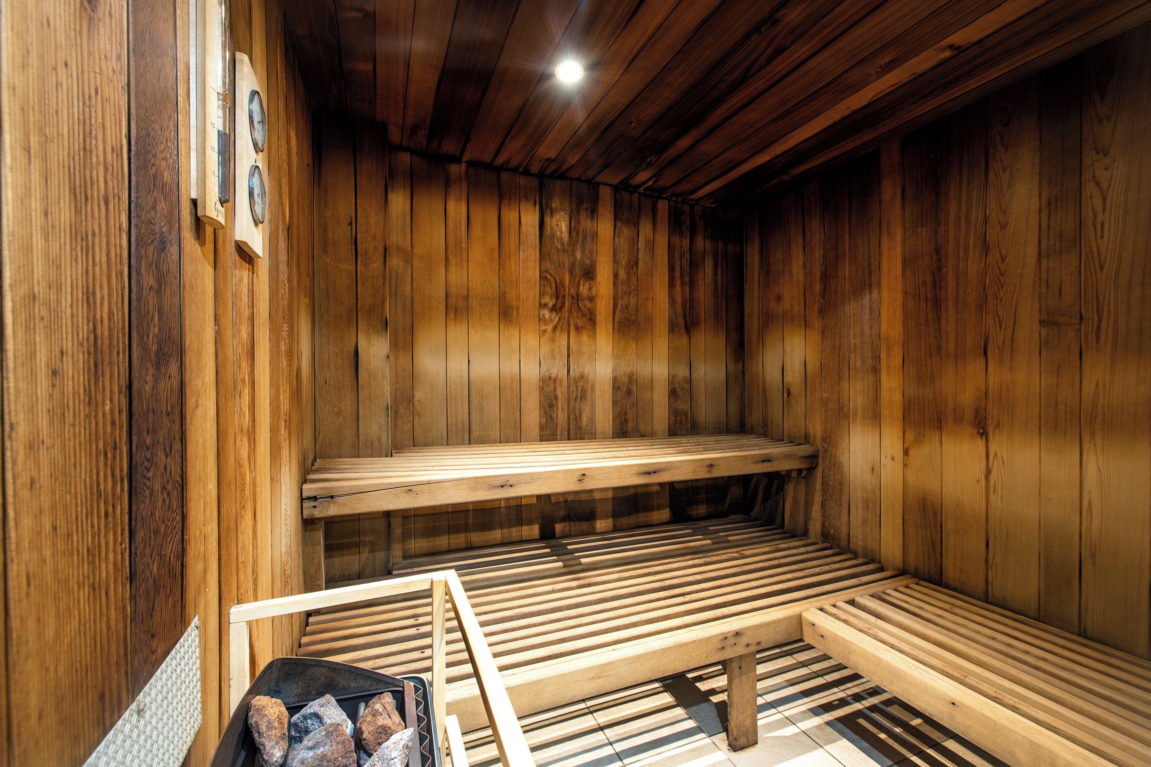 A wooden sauna with benches and a bench with a towel rack.