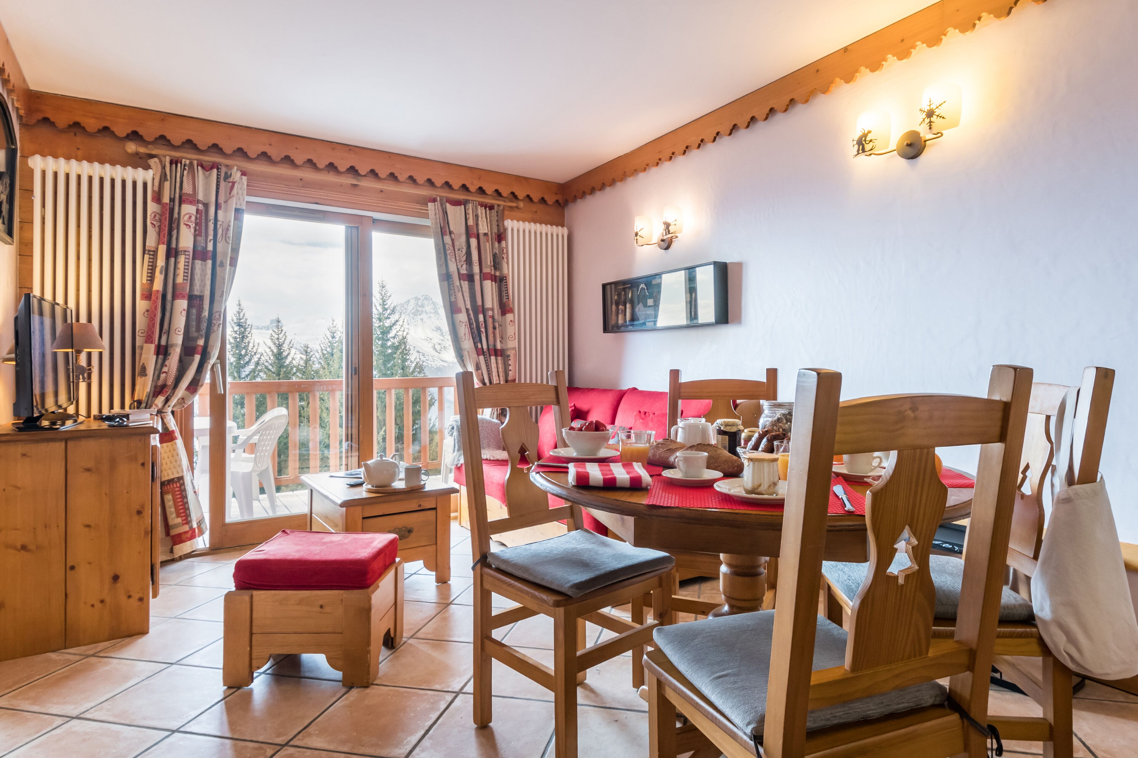 A cozy dining area with wooden furniture, a red cushioned bench, and a table set with dishes and cups.