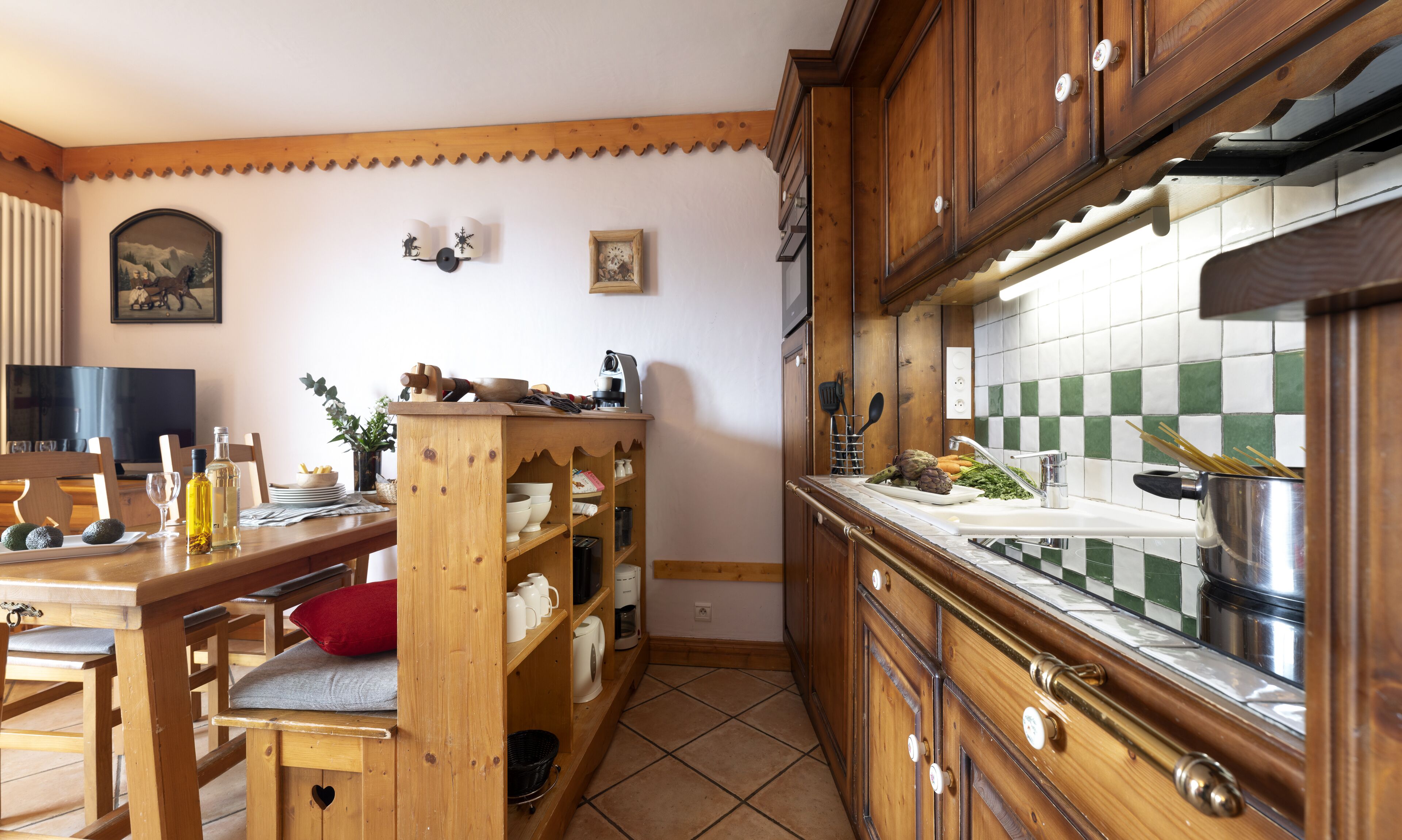 Une cuisine avec des meubles en bois, un pare-feu en carreaux et un coin repas comprenant une table et des chaises en bois.