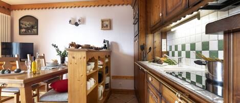 A kitchen with wooden cabinets, a tiled backsplash, and a dining area with a wooden table and chairs.