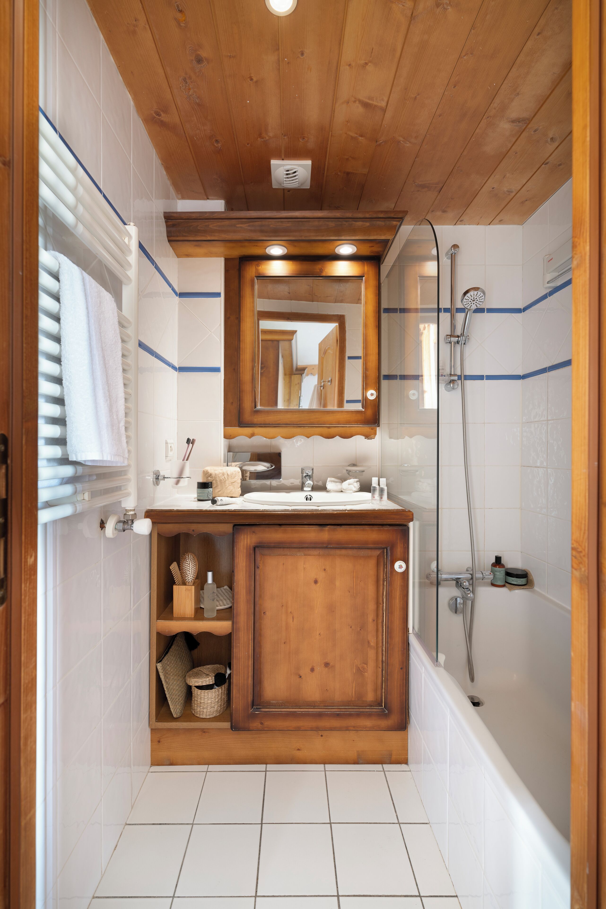 Un baño con tocador de madera, espejo, bañera y ducha.