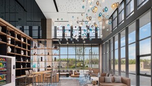 A spacious lobby with a modern design, featuring a seating area with sofas and chairs, a vending machine, and a large window offering a view of the outdoors. - Fairfield by Marriott Liaocheng Dongchangfu (Liaocheng)