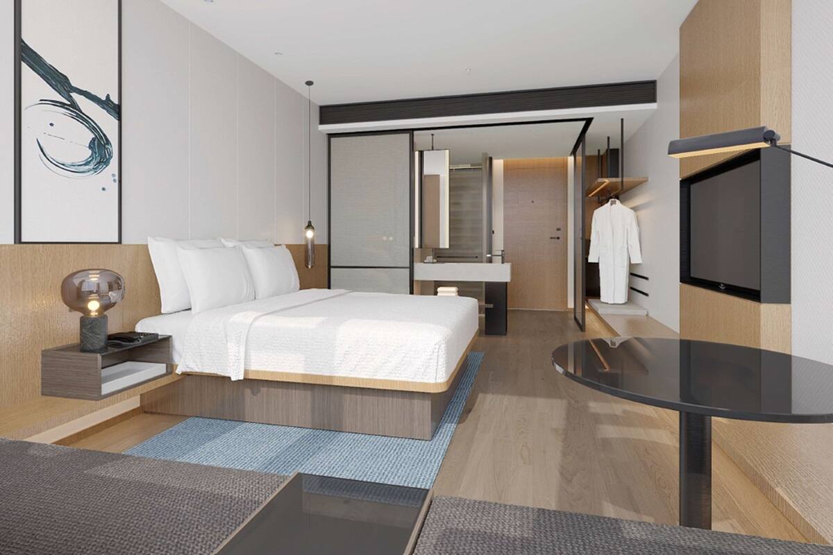 Ein modernes Hotelzimmer mit einem großen Bett, Nachttisch und Fernseher.