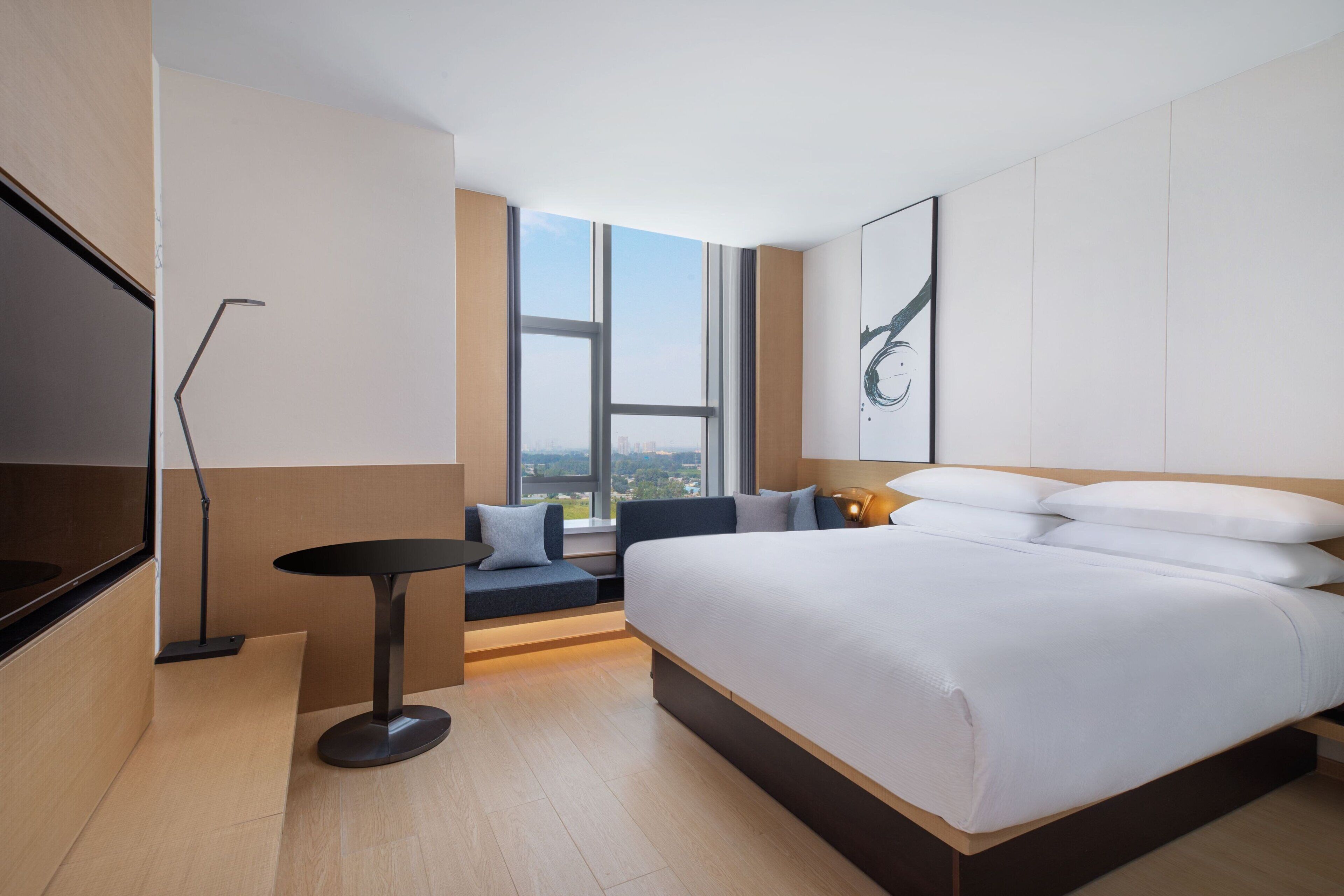 Une chambre d’hôtel moderne dotée d’un grand lit, d’un coin salon avec vue et d’une télévision à écran plat.