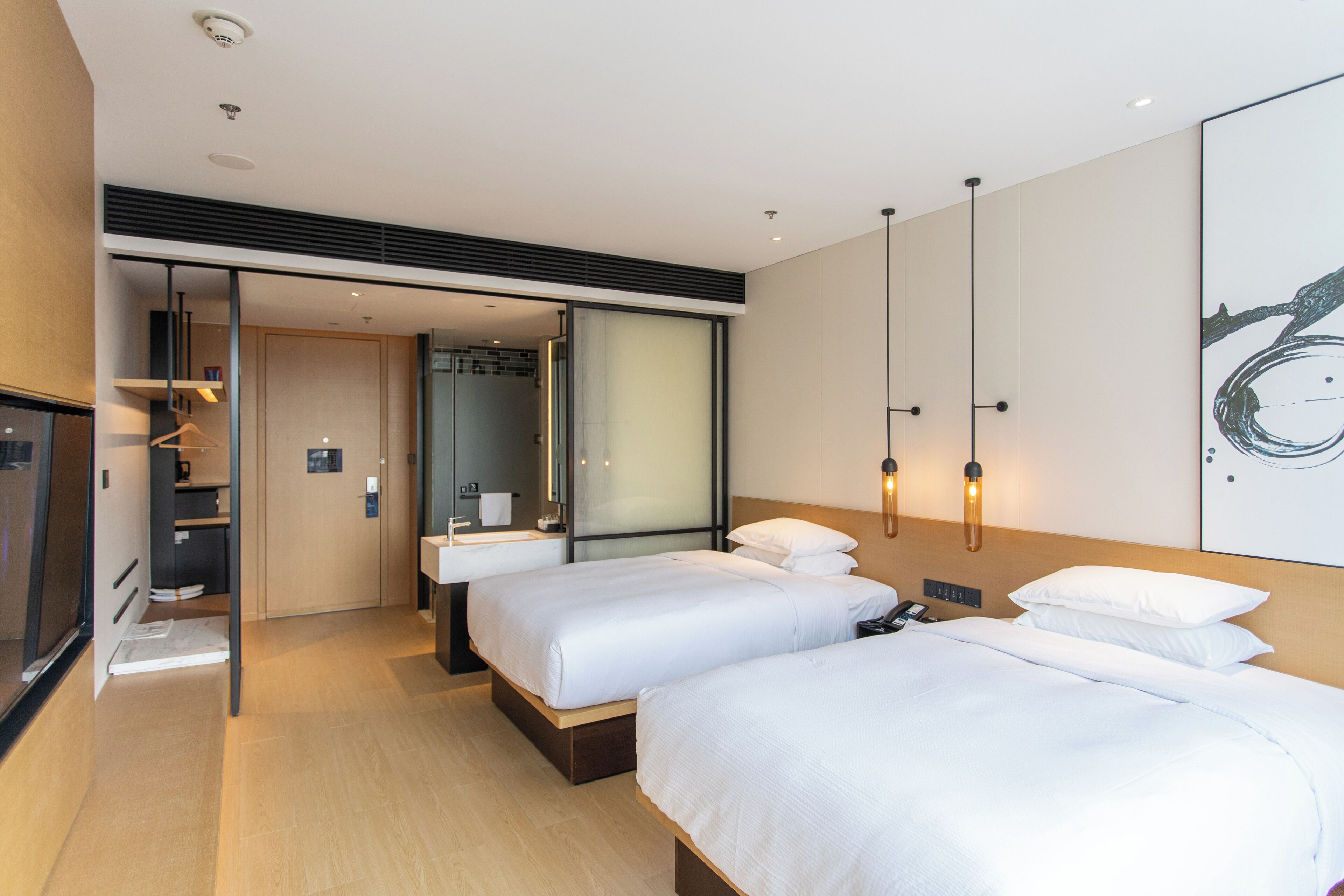 Une chambre d’hôtel avec deux lits, une salle de bain, une armoire et un grand miroir.