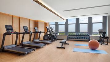 A modern gym with treadmills, elliptical machines, a bench, and an exercise ball.