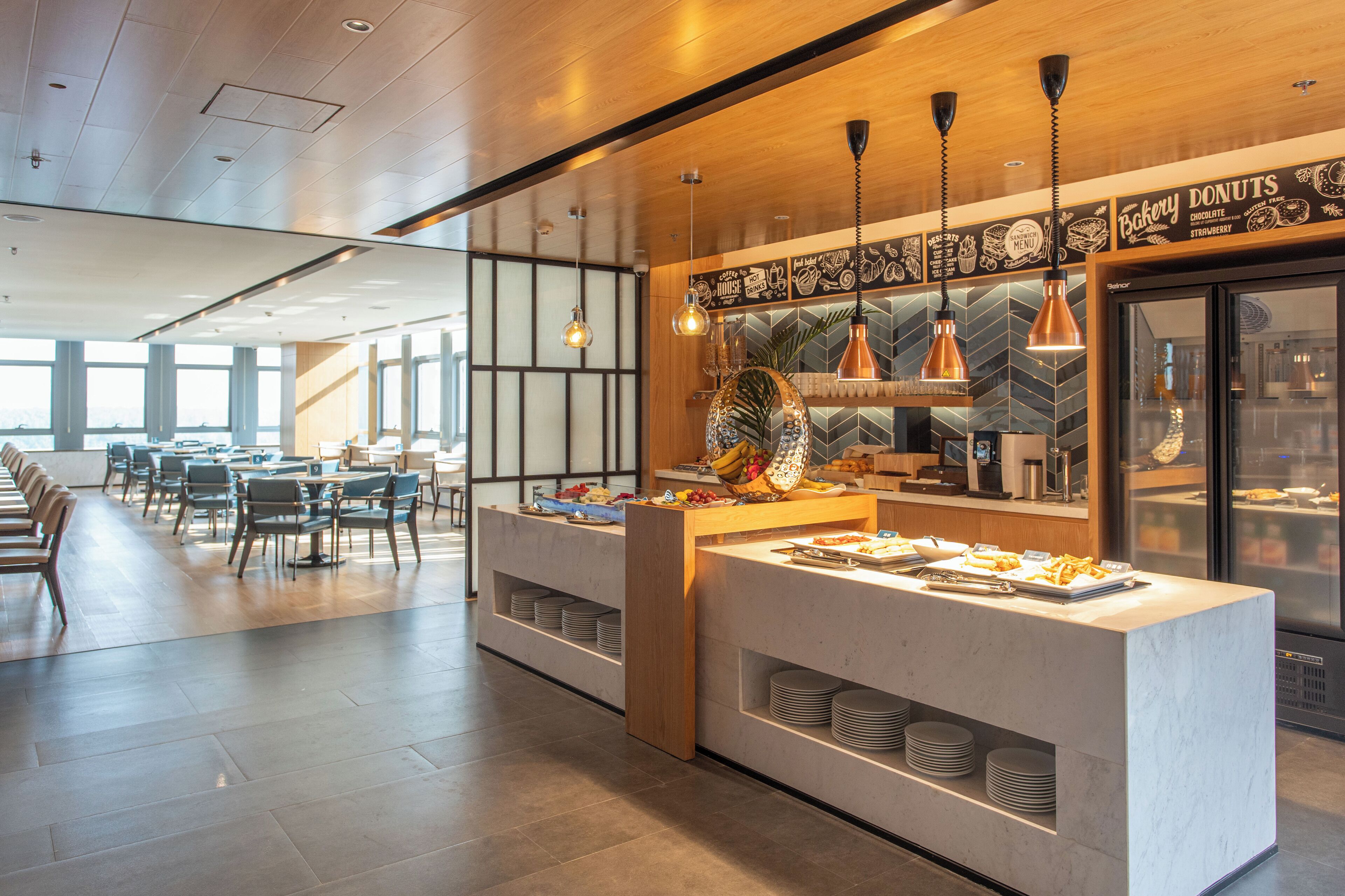 A modern dining area with a buffet setup, including a variety of food items and a coffee station.
