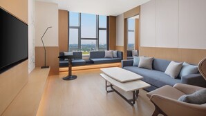 A modern living room with a large flat-screen TV, a sofa, a coffee table, and a floor lamp. - Fairfield by Marriott Liaocheng Dongchangfu (Liaocheng)