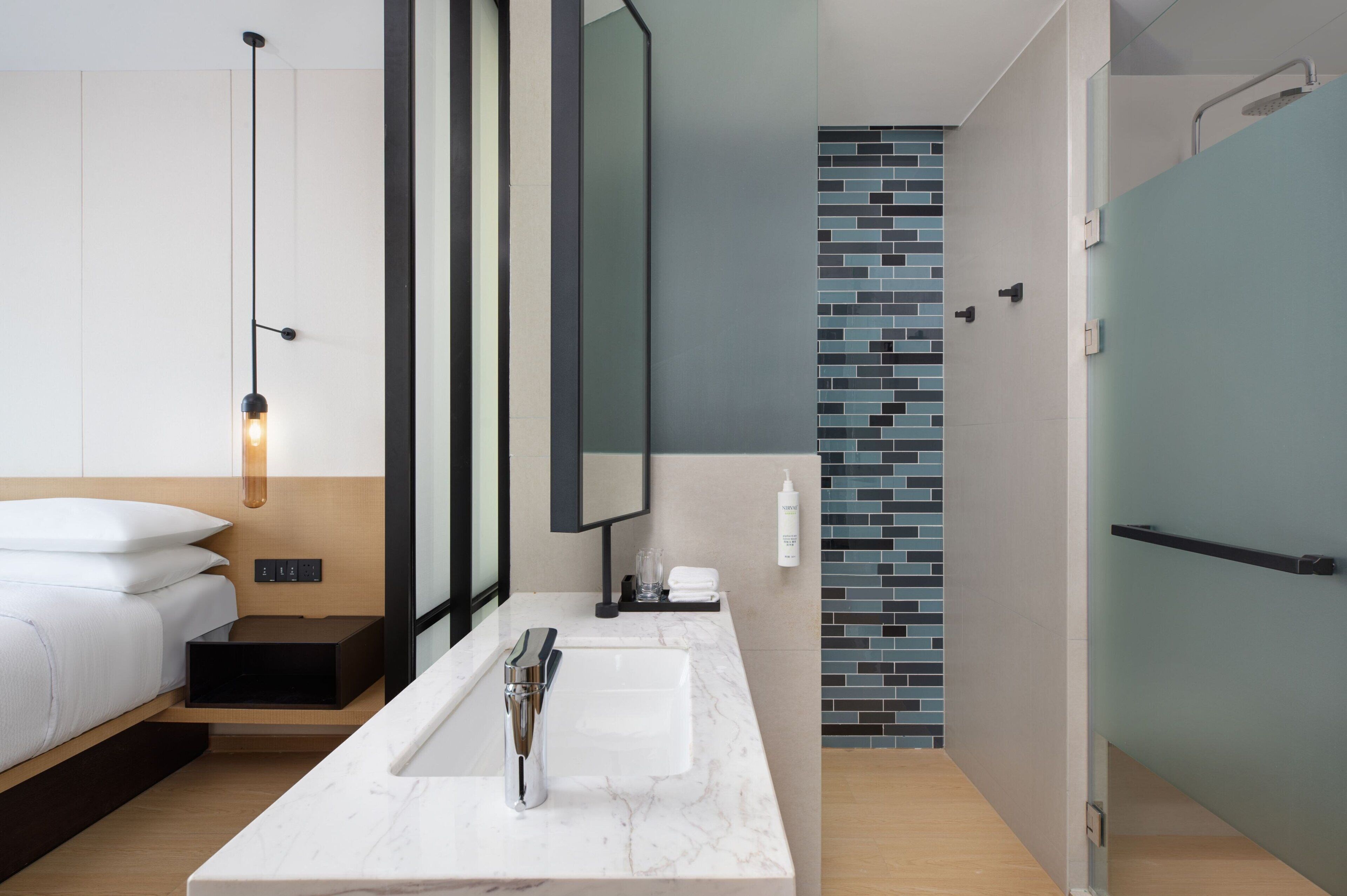 A modern bathroom with a large mirror, a white sink, and a shower area.