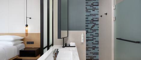 A modern bathroom with a large mirror, a white sink, and a shower area.