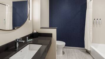 Une salle de bain moderne avec un lavabo noir, des toilettes blanches et une baignoire.
