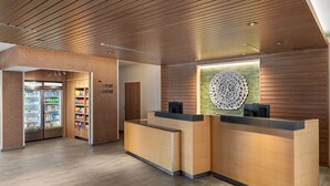 A modern reception area with wooden paneling, a reception desk, and a refrigerated display case. - Fairfield Inn & Suites by Marriott Yankton (Yankton)