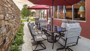 A patio with outdoor seating, stone wall, and large windows. - Fairfield Inn & Suites by Marriott Yankton (Yankton)