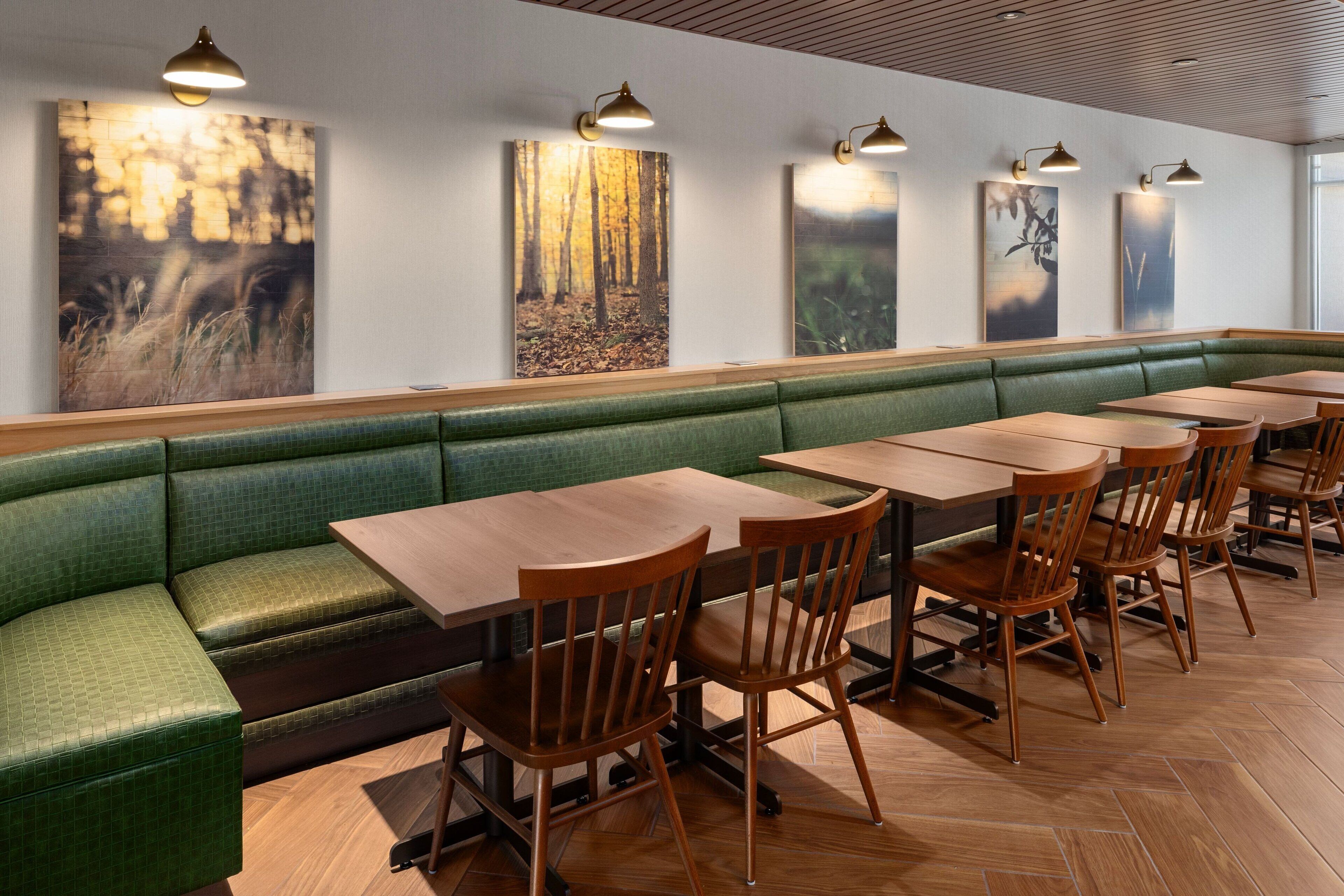 Ein Restaurant mit einer grünen gepolsterten Bank, Holztischen und -stühlen.