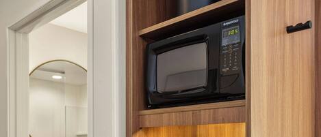Una kitchenette compacta con cafetera, microondas y refrigerador.