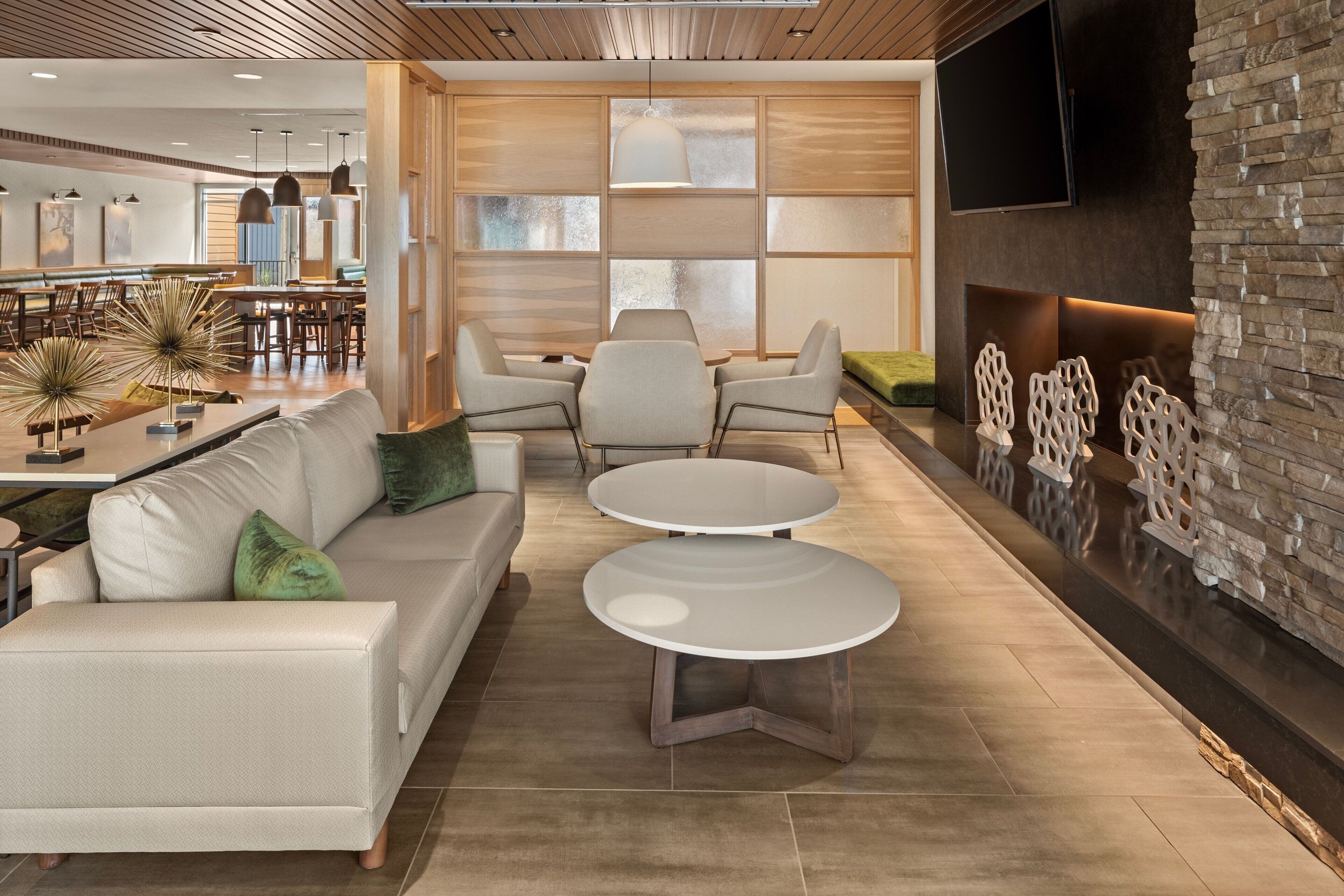 A modern living room with a sofa, two round tables, and a fireplace.